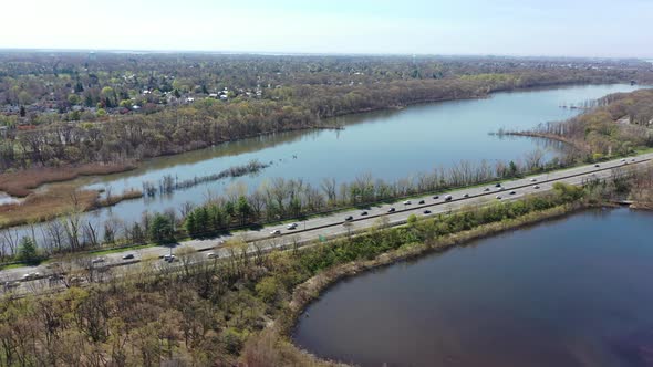 An aerial view over some reflective lakes during the day. The drone truck right along side the parkw alt