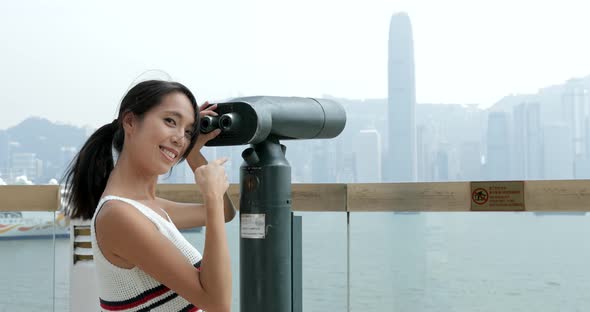 Woman travel in Hong Kong and looking though tourist binocular  alt