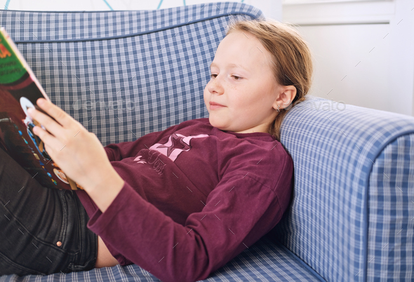 teenager girl reading a book and relaxing on the sofa.