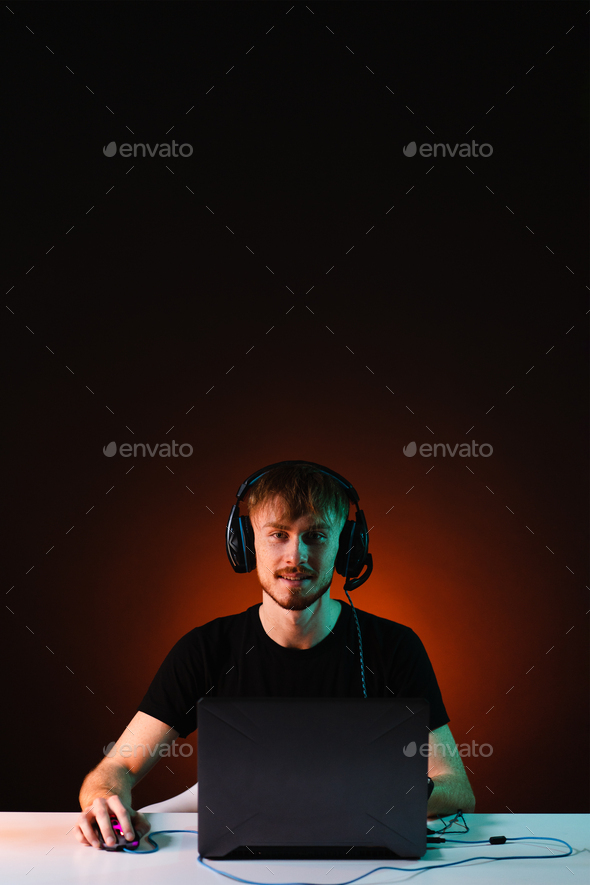Gamer playing video games with headphones on neon light background