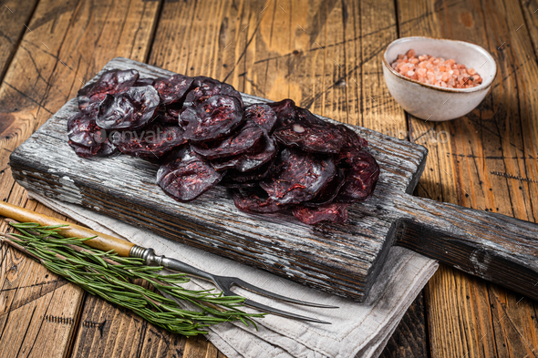 Horse game meat cured sausage with rosemary on a cutting board. Wooden background. Top view
