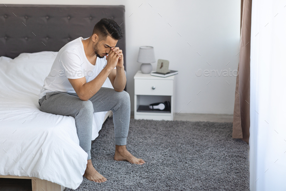 Seasonal Depression. Portrait Of Upset Arab Man Sitting On Bed At Home