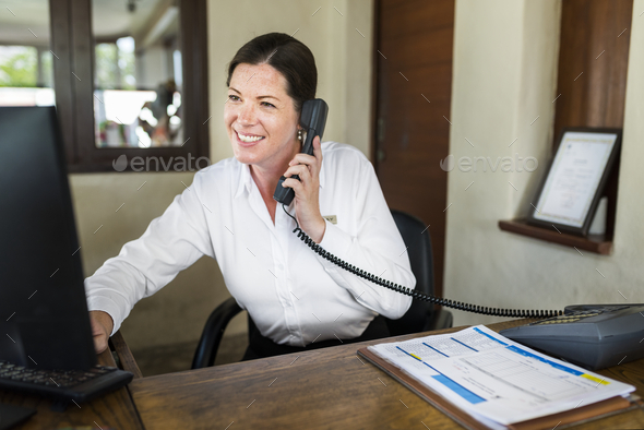 Female resort receptionist working at the front desk - Stock Photo - Images