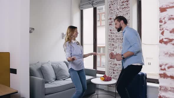 Guy and His Pretty Blond Girlfriend Dancing Together in their Room of Hotel alt