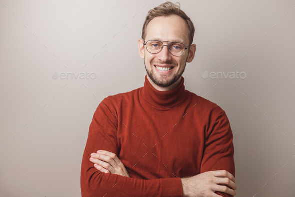 Portrait of smiling caucasian man wearing glasses and red turtleneck on gray background