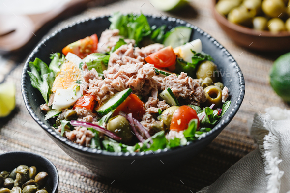 Canned tuna salad with fresh vegetables, capers and olives in a black bowl - Stock Photo - Images