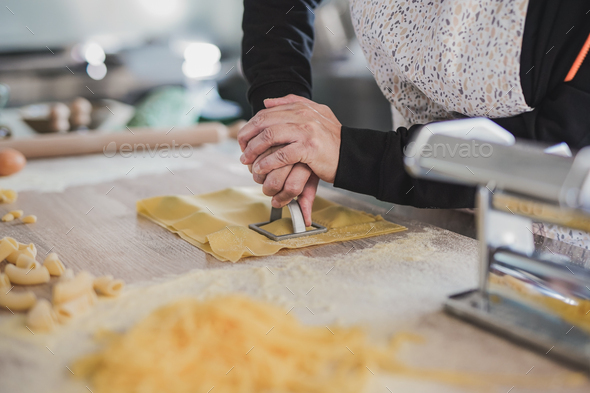 Woman working inside pasta factory and stamping fresh made ravioli