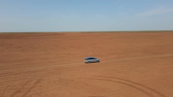 Car Moving Across Horizonless Arid Steppe in Kalmykia Russia alt