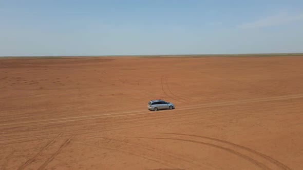 Car Moving Across Horizonless Arid Steppe in Kalmykia Russia
