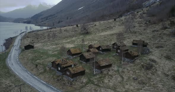 Aerial shot of small fairytale village in Norwegian wilderness, rooftops covered by moss, Cloudy alt
