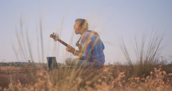 Musician Plays Bass Guitar Outdoors alt
