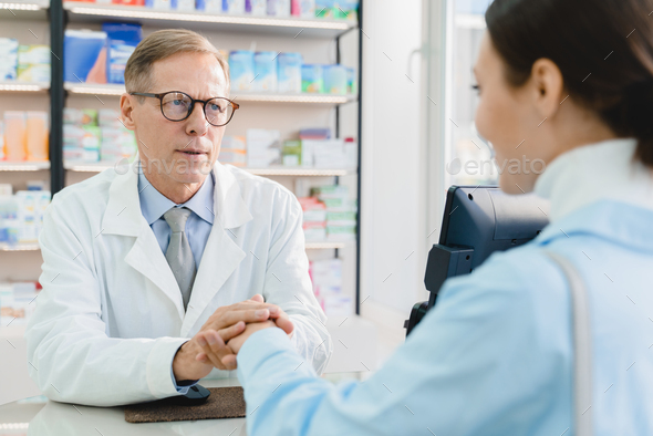 Pharmacist doctor supporting customer client buyer, listening attentively to her medical complaints