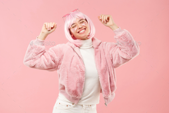 Excited teen girl dancing to sounds of music, wearing fur coat and colored hair at party