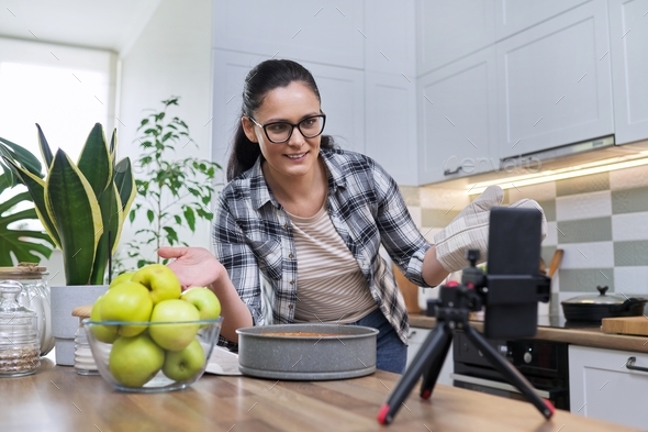 Female recording video of an apple pie recipe on smartphone at home in the kitchen