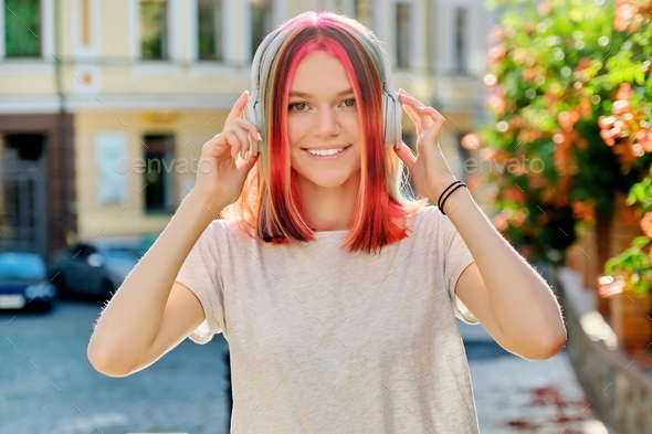 Outdoor portrait of positive trending young female teenager in headphones