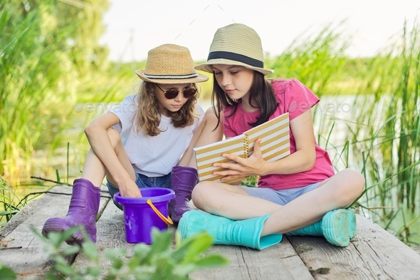Children two girls resting playing reading their notebook in nature