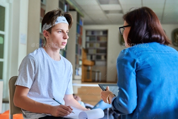 Woman school psychologist talking and helping student, teenage boy