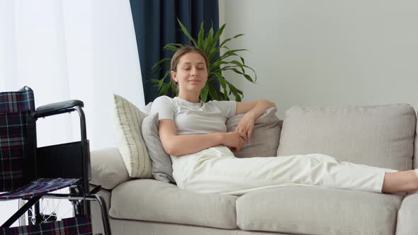 Portrait of Young Woman with Wheelchair Looking at Camera in Living Room alt