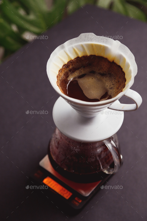 Brewing ground coffee through paper filters into a glass coffee pot