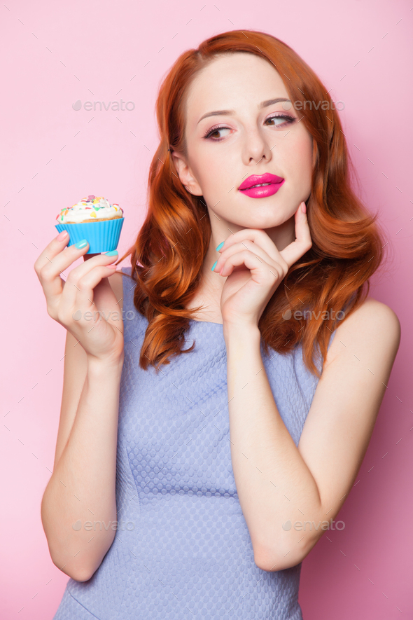 Redhead girl with cupcake in pink background. Stock Photo by Masson-Simon