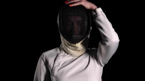 Portrait of a Confident Fencer Looking at the Camera and Putting on a Protective Mask on a Black alt