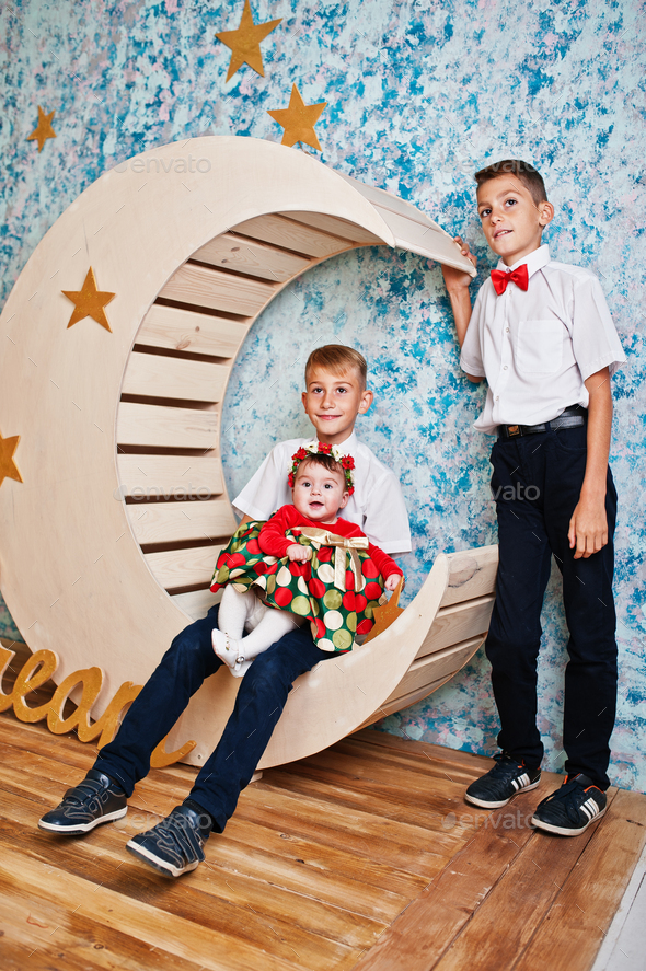 Two brothers with baby sister sitting on moon decoration with sign dream