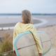 Senior woman walking towards beach, carrying surfboard, rear view - PhotoDune Item for Sale
