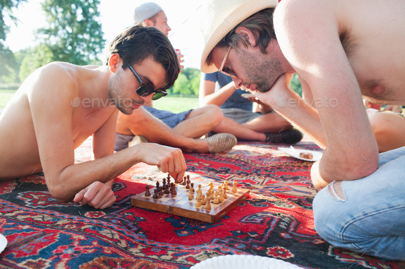 Two young men playing board game at sunset park party