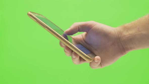 A single hand scrolling through a social media platform with a  smartphone on a green screen backgro alt