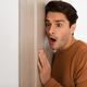 Shocked young guy listening through the door - PhotoDune Item for Sale