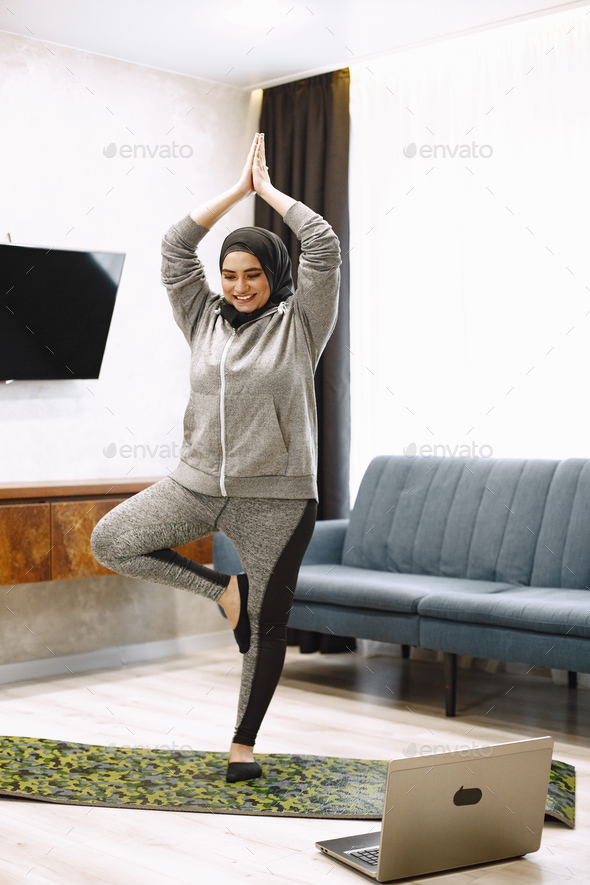 Woman Doing Yoga While Watching Instructional Videos On Laptop