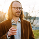 White ginger man in eyeglasses drinking coffee at city street - PhotoDune Item for Sale