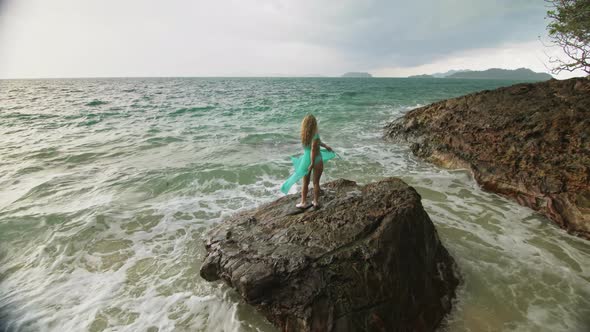 Woman Walks on Rock of Sea Reef Stone Stormy Cloudy Ocean alt