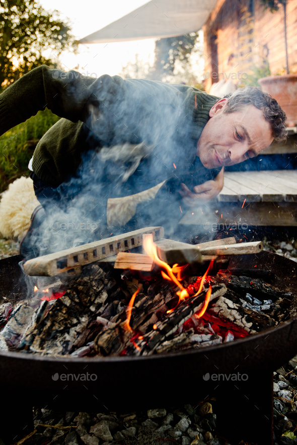 Mature man leaning to inspect fire pit