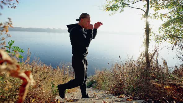 Handsome Young Guy Standing in Fighting Stance and Performing Exercises While Standing on Steps Near alt