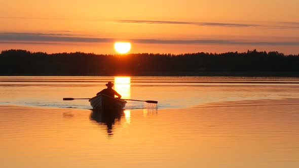 Sunset over Lake and Man Rowing on Boat 