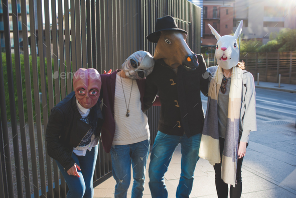 portrait of young people with funny masks standing in the street and looking camera