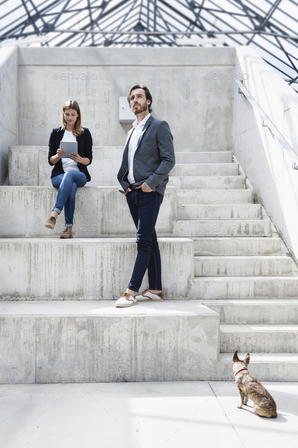 Two business people and a dog in modern architecture - Stock Photo - Images