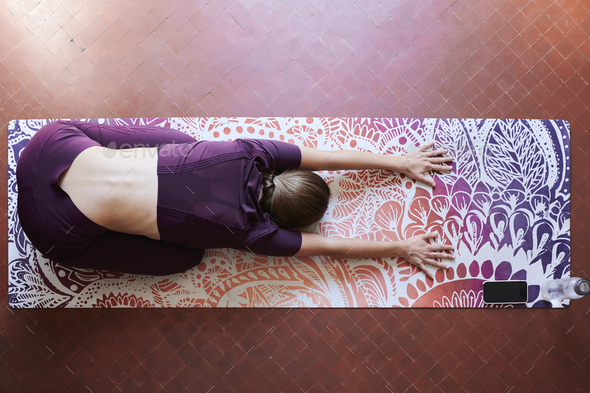 Young brunette woman practising yoga in student dorm, child position from above