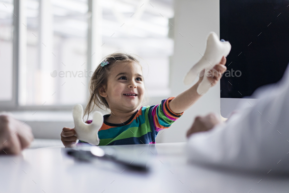 Portrait of smiling girl with tooth model at desk in medical practice