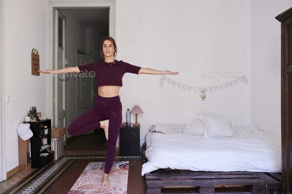 Young brunette woman practising yoga in student dorm