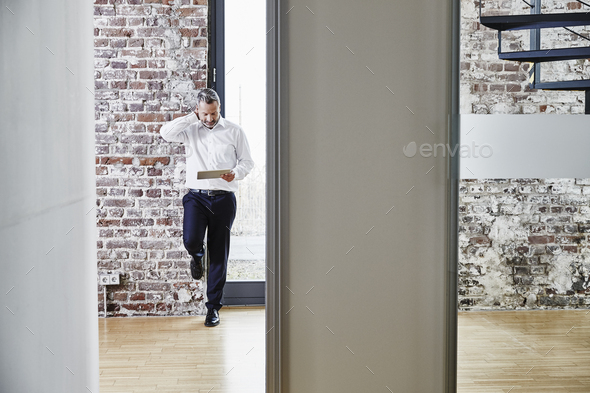 Businessman looking at tablet on modern office floor - Stock Photo - Images