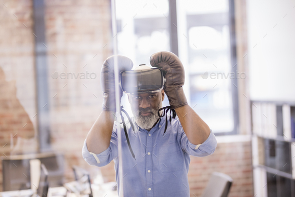 Portrait of businessman with Virtual Reality Glasses and boxing gloves in the office - Stock Photo - Images
