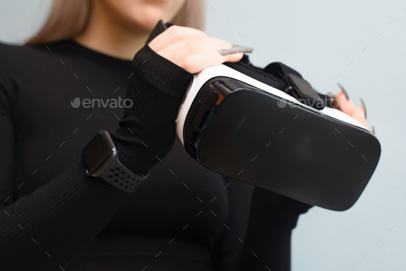 Young woman holding VR glasses in her hands, close-up. Girl using interactive device, indoors. New