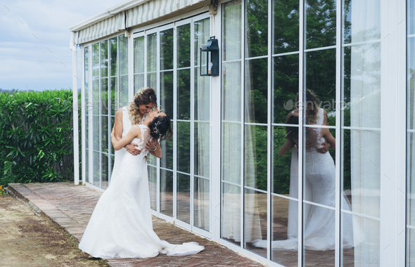 Portrait of a proud couple kissing each other with white wedding dresses. Reflection