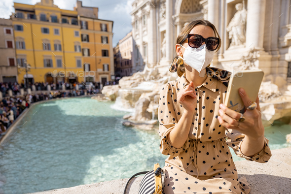 Woman in face mask visiting famous di Trevi fountain in Rome