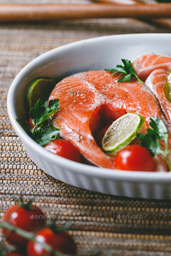 Fresh salmon steaks with lime, cherry tomatoes, parsley and olive oil. - Stock Photo - Images