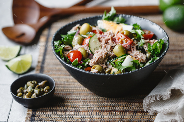 Canned tuna salad with fresh vegetables, capers and olives in a black bowl - Stock Photo - Images