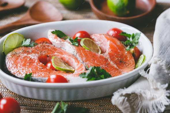 Fresh salmon steaks with lime, cherry tomatoes, parsley and olive oil. - Stock Photo - Images