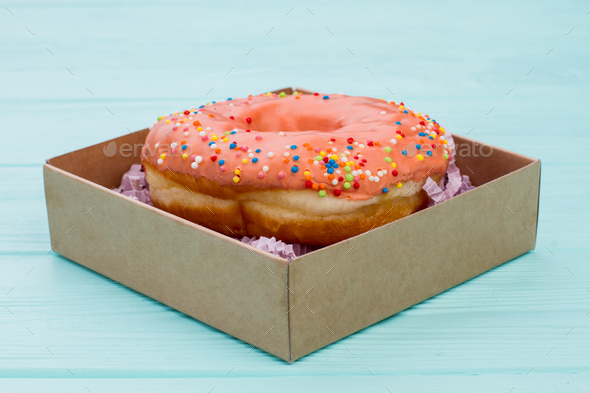 Donut in box on blue wooden background.